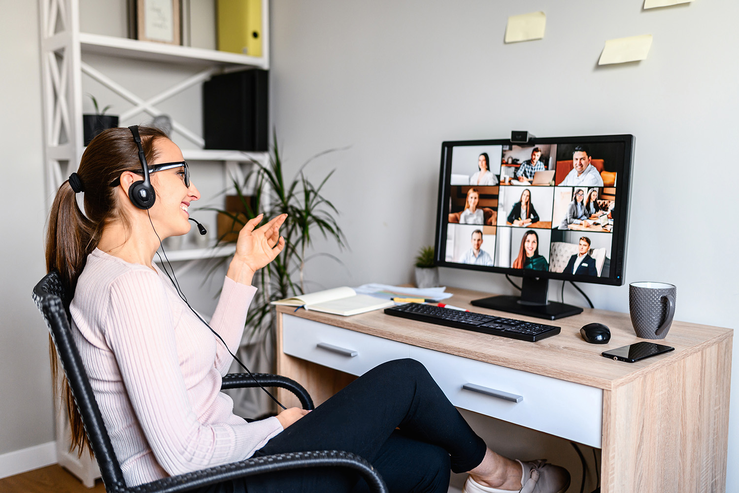 Woman at her home office sitting on chair with headset on in a Zoom meeting on her computer.